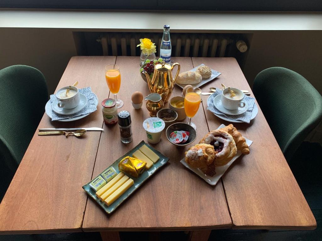 una mesa de madera con alimentos para el desayuno y bebidas. en Maison d'Artiste, en Gante