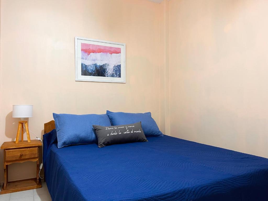 1 dormitorio con cama azul y almohada en Dpto 2 AMB cerca de la playa en Santa Teresita en Santa Teresita