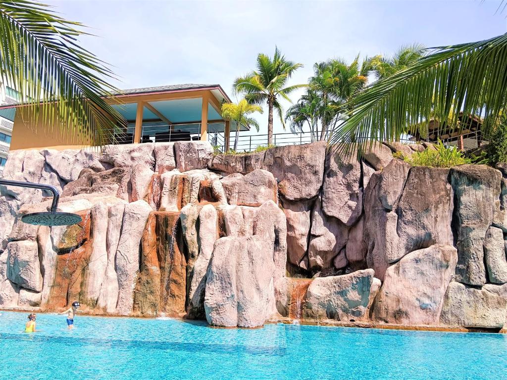 a pool with a rock wall and people in the water at Laguna Beach Resort 3 Maldives in Jomtien Beach