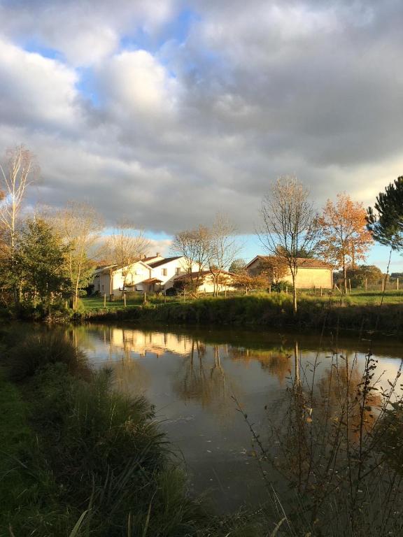 a house sitting next to a river with a building at Maison d hôtes Les Chantours dans réserve naturelle 15 hectares in Saint-Antoine-Cumond