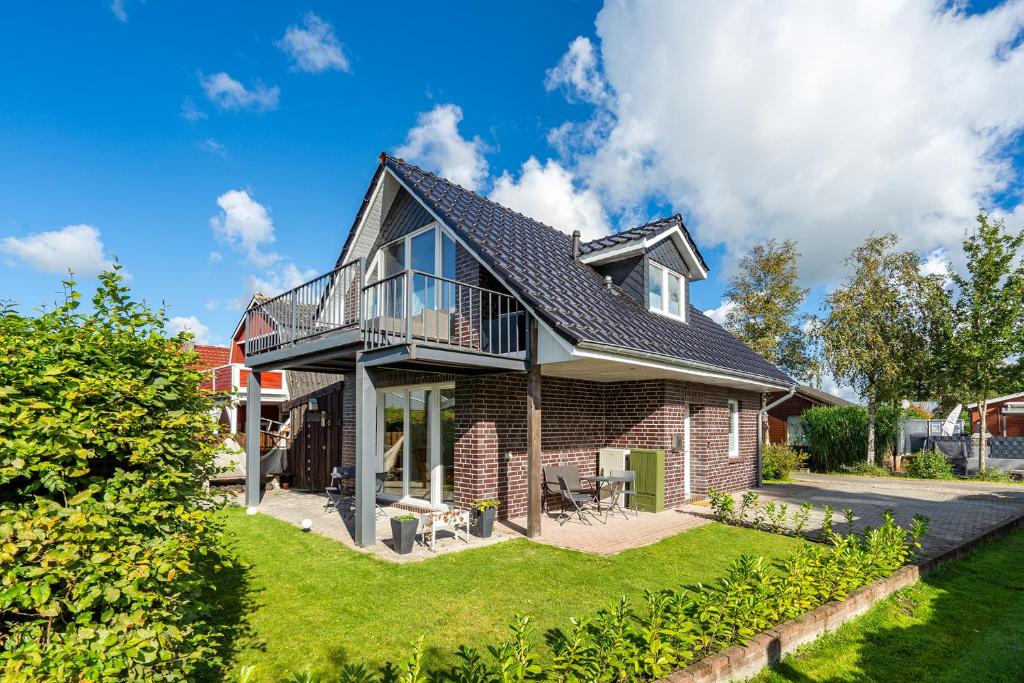 a brick house with a balcony on a lawn at Haus am See, exquisites Relaxen in Südbrookmerland