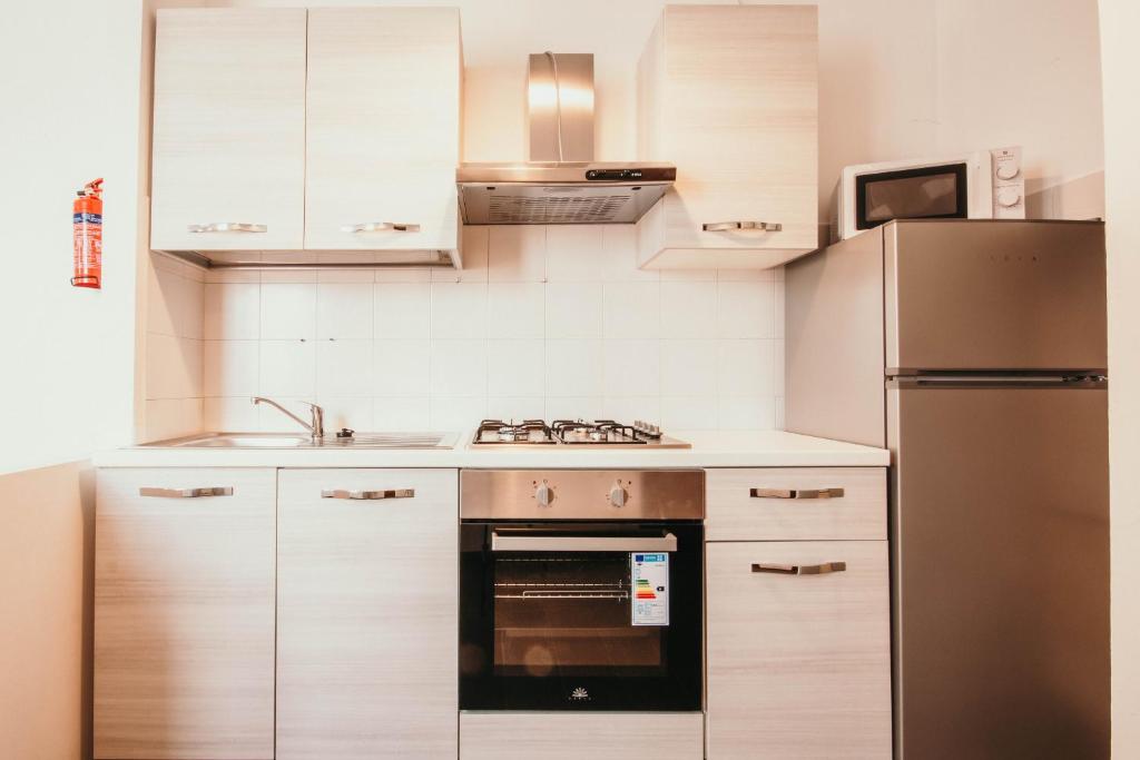 a kitchen with white cabinets and a stainless steel refrigerator at Appartamento Cairoli - Affitti Brevi Italia in Varese