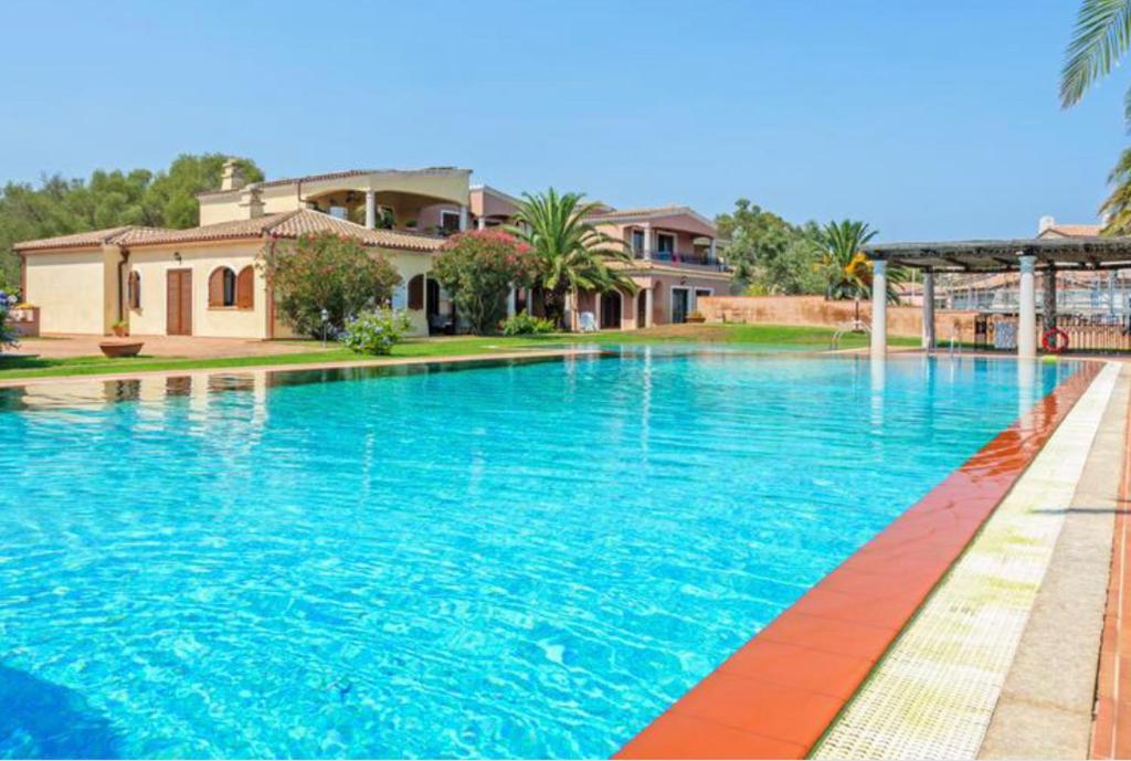 a large swimming pool in front of a house at Appartamento Le Palme Costa Smeralda in Arzachena