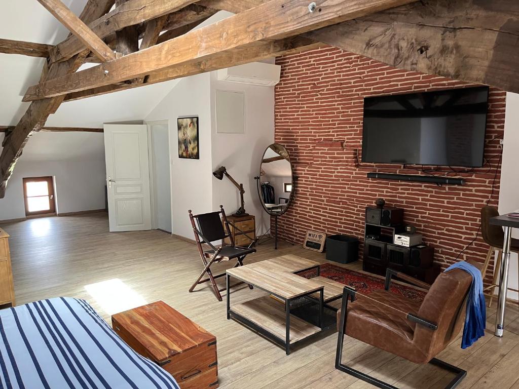 een woonkamer met een bakstenen muur en een flatscreen-tv bij Les chambres du Golf in Espalais