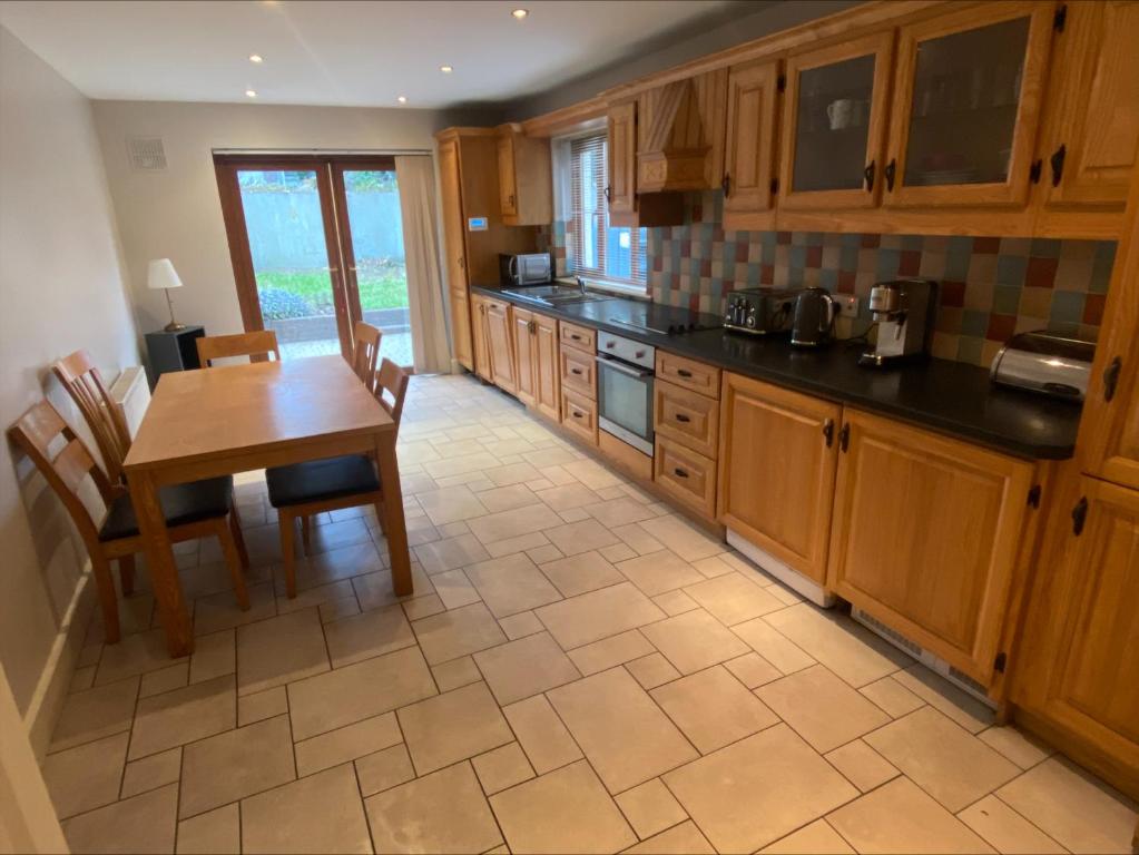 a kitchen with wooden cabinets and a table and chairs at Cosy 4 Bedroom Galway House with Rear Garden Patio in Galway