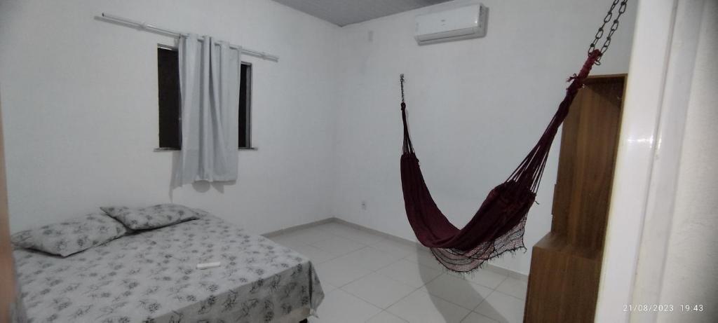 a room with a bed and a hammock in it at casa temporada em Barreirinhas in Marinheiros