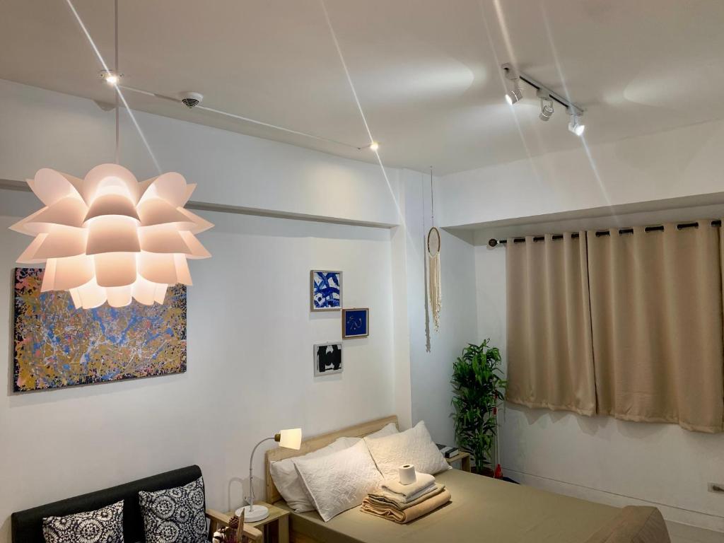 a bedroom with a bed and a chandelier at Scandi Minimalist Mckinley Hill BGC in Manila