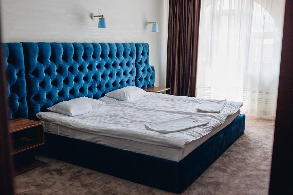 Bett mit blauem Kopfteil in einem Schlafzimmer in der Unterkunft River Stone Hotel in Scheschory