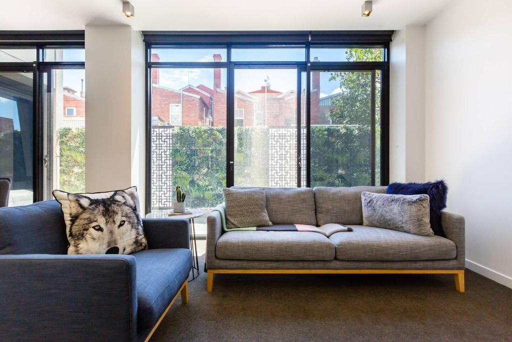 ein Wohnzimmer mit 2 Sofas und einem großen Fenster in der Unterkunft Richmond Chic off Bridge Rd with Patio Parking in Melbourne