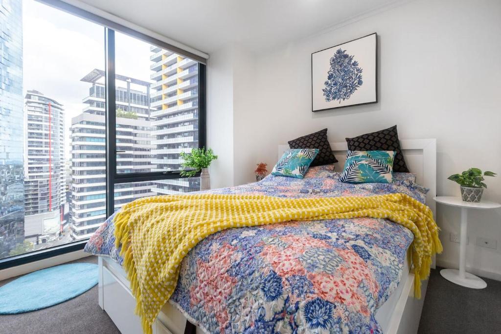 a bedroom with a bed and a large window at Southbank Splendour - A Sky High Stay with Parking in Melbourne