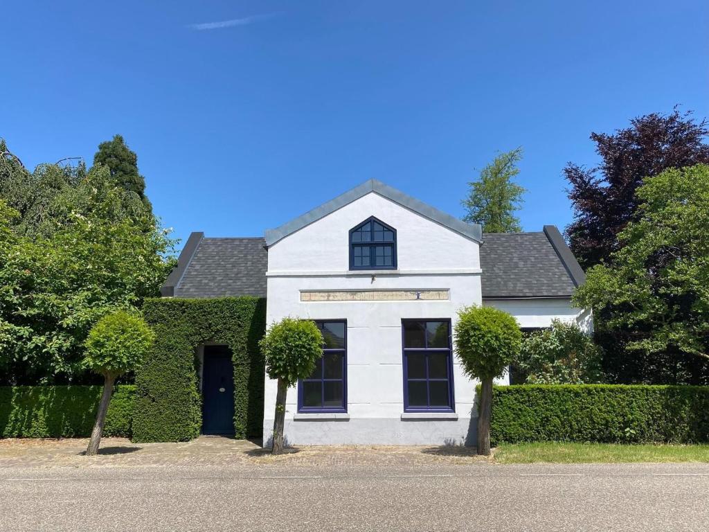 a white house with a green hedge at Holiday home in rural area with private garden in Leende