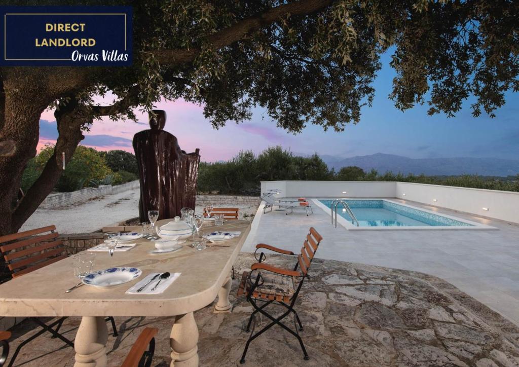 einen Tisch und Stühle neben einem Pool in der Unterkunft Villa Dubrava Tranquil Retreat Nestled in an Olive Grove for Serene Escapes in Pučišća