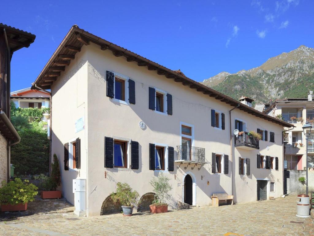 a white building with black windows and a mountain at Traditional Apartment in Poffabro with Fireplace in Frisanco