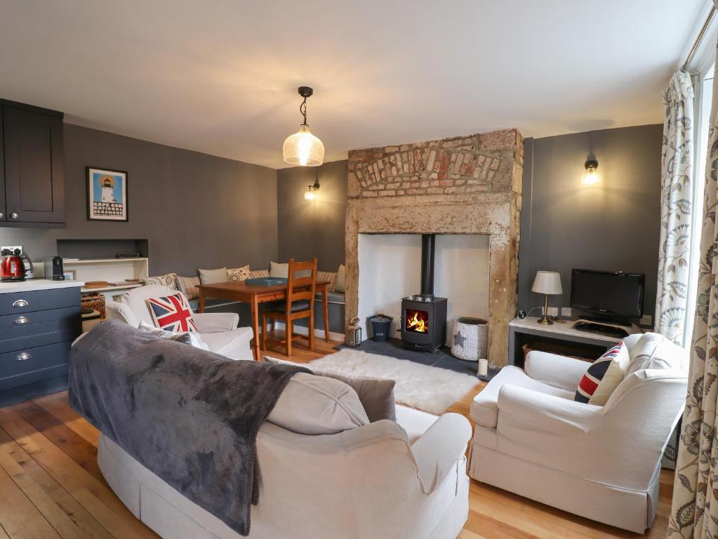 a living room with two white couches and a fireplace at Grebe Cottage in Alnwick