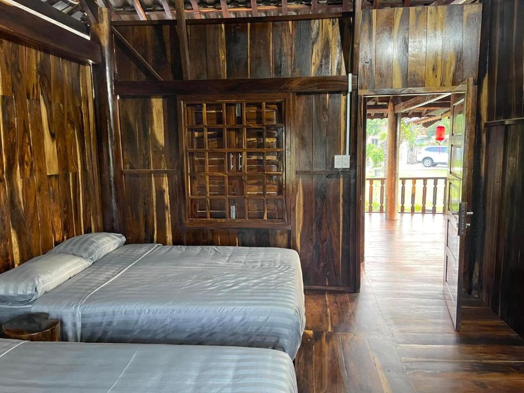 a bedroom with two beds and a wooden wall at Highland garden - homestay Phú Yên 