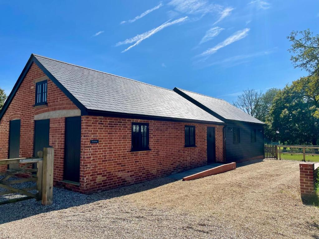 a red brick barn with a fence in front of it at The Old Dairy in Chappel