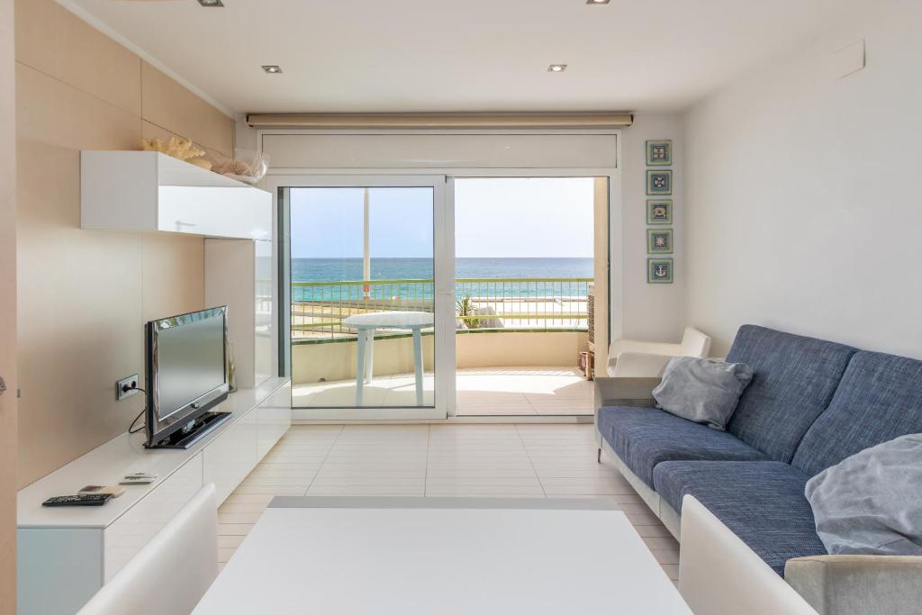 a living room with a blue couch and a view of the ocean at Super Beach 2 in Platja  d'Aro
