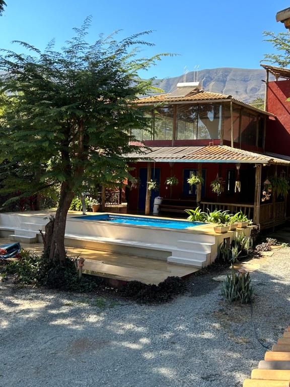 uma casa com piscina ao lado de uma árvore em A Mi Manera Pousada , cerveja própria e Bistrô ! em Brumadinho