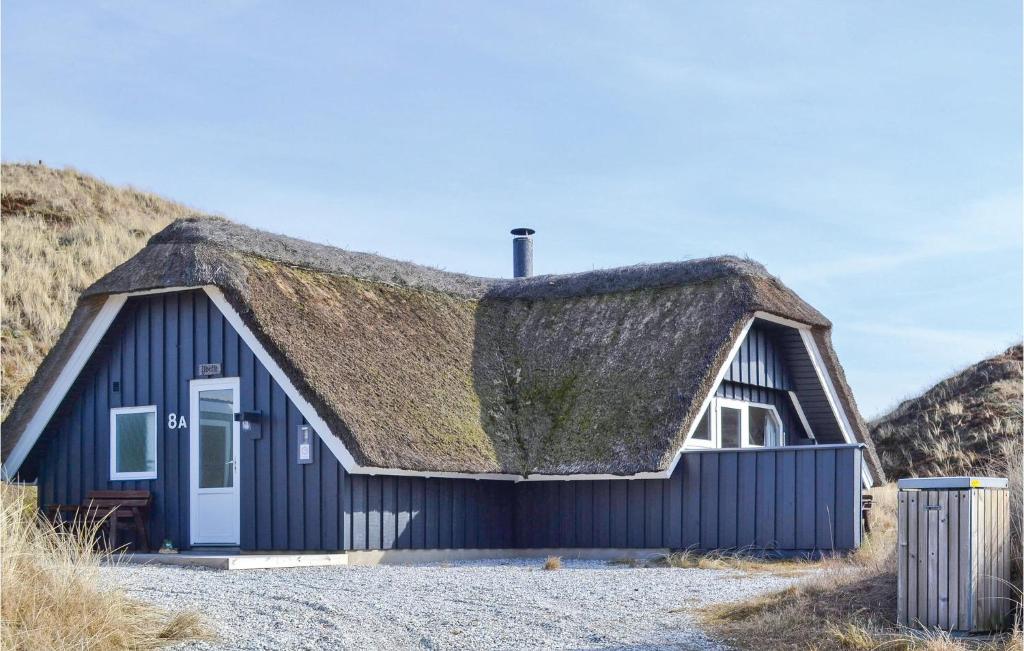 a black house with a thatched roof with a trash can at 2 Bedroom Awesome Home In Hvide Sande in Havrvig