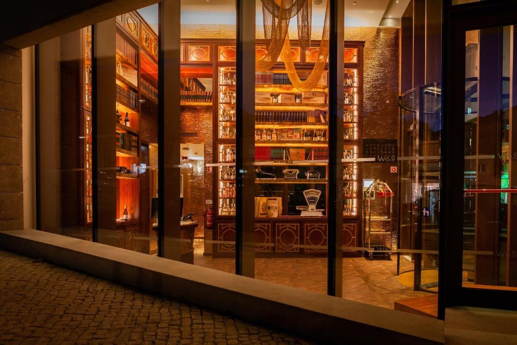 A warmly lit glass-fronted hotel library and lounge visible from the street.