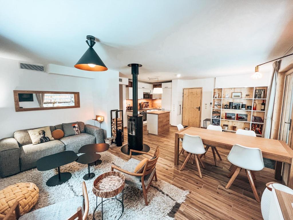 een woonkamer met een bank en een tafel en stoelen bij Le Peyra, Apt 4 personnes avec terrasse et jardin in Le Monêtier-les-Bains
