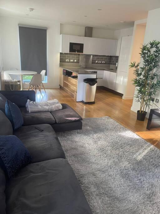 a living room with a couch and a kitchen at Luxurious NEW 2 Bed apartment in London