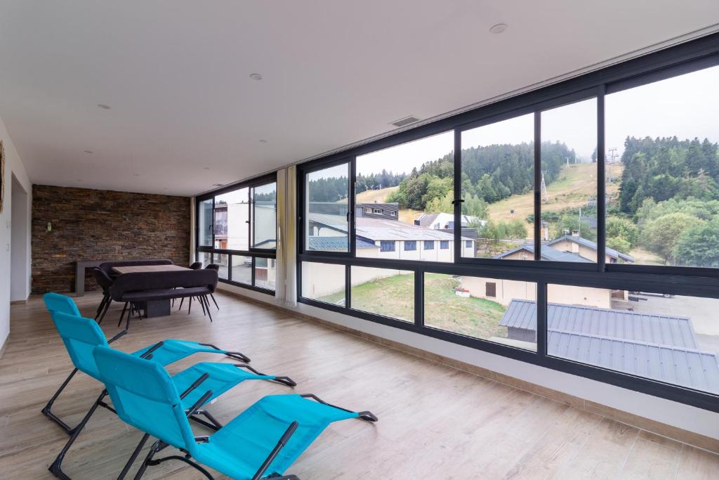 a room with chairs and a table and windows at Résidence pieds des pistes in Ax-les-Thermes