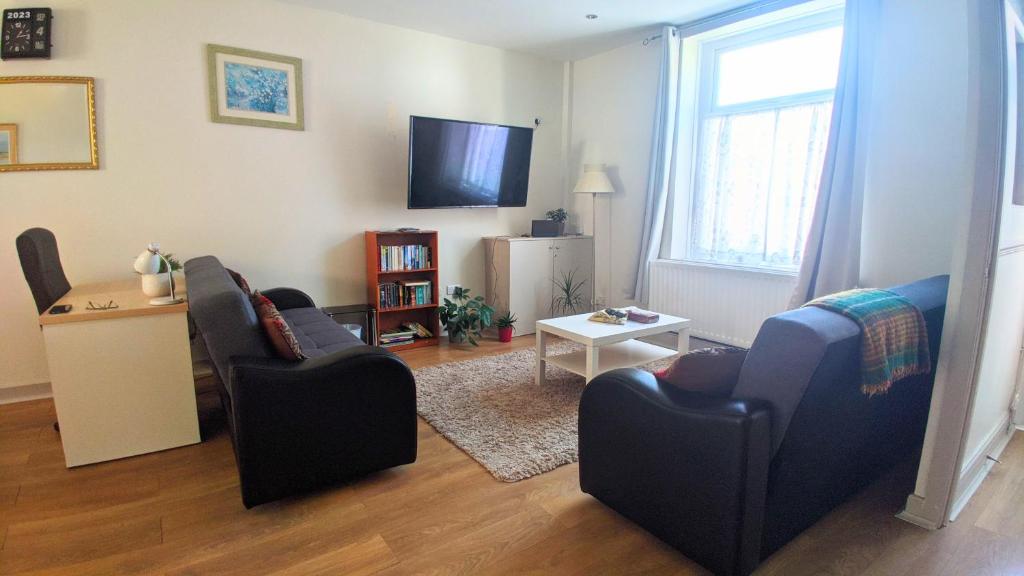 a living room with two chairs and a tv at Modern holiday let in Skipton, North Yorkshire in Skipton