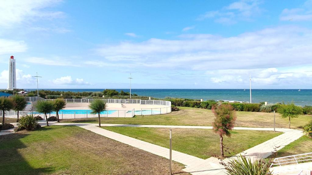 une piscine avec l'océan en arrière-plan dans l'établissement Grand Bleu-Studio vue sur mer - piscine, à Les Sables-dʼOlonne