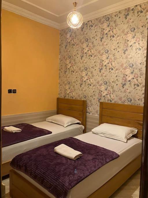 two twin beds in a room with flowers on the wall at Maison Typique Marocaine@WIFI Fibre Optique in Agadir