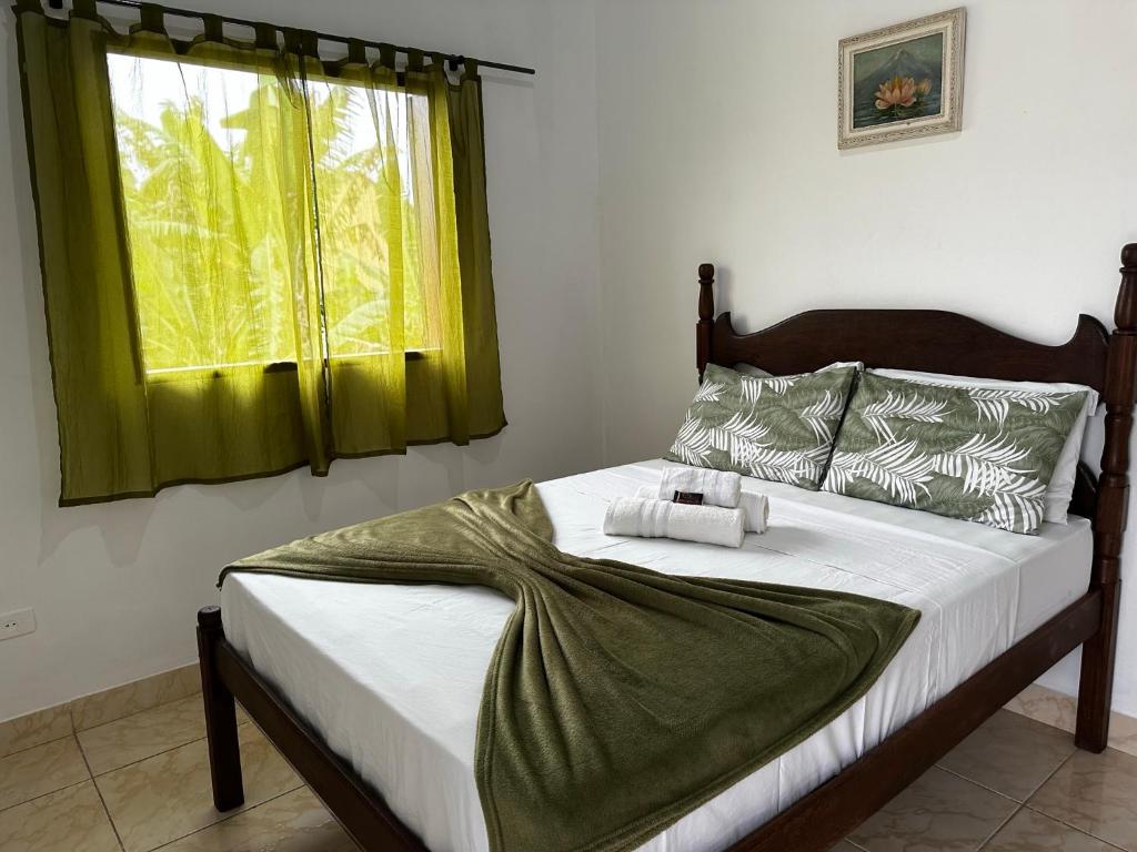 um quarto com uma cama com uma cortina verde e uma janela em Casa Perto do Centro em Paraty