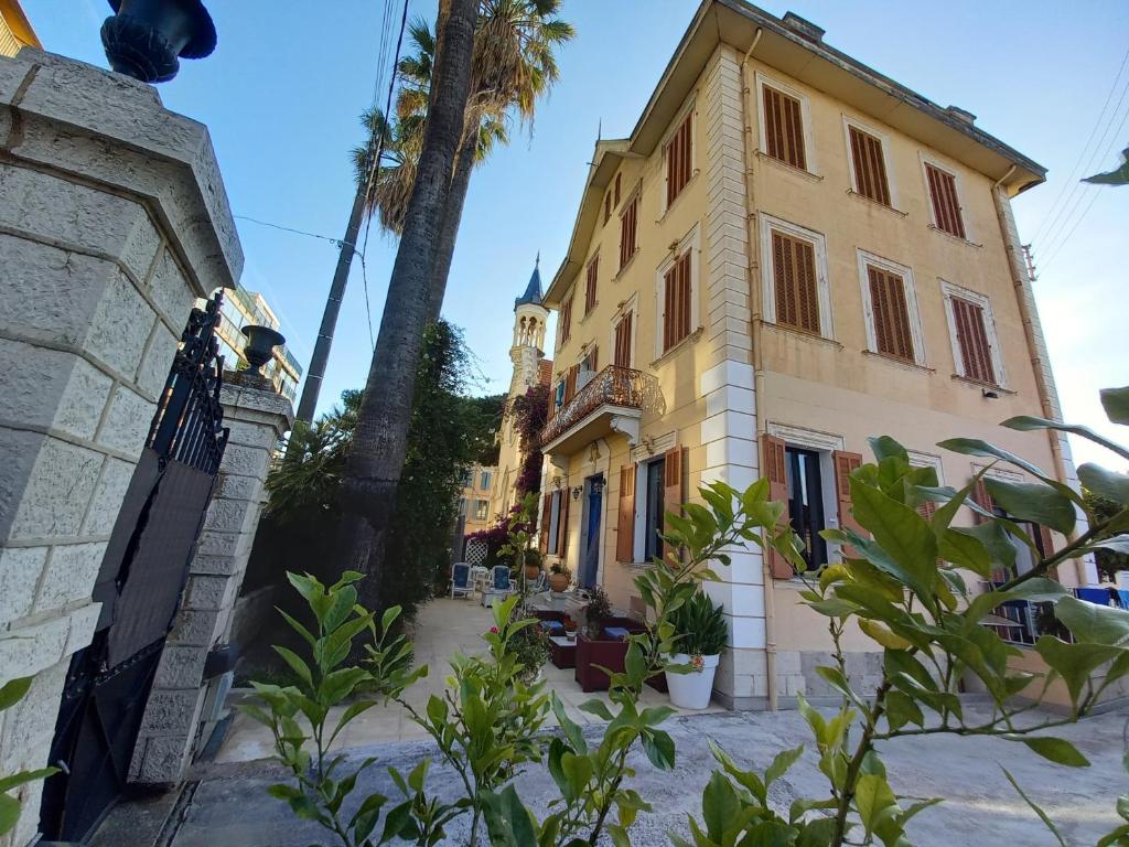 un bâtiment jaune avec un palmier devant lui dans l'établissement La MASCOTTE 3, à Vallauris