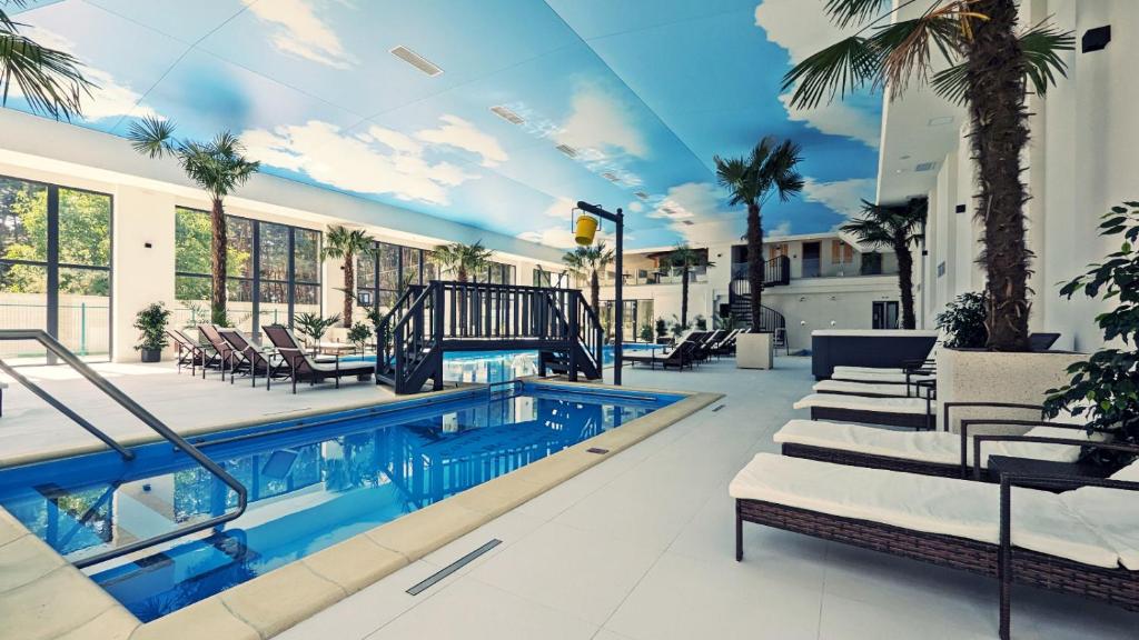 a swimming pool in a house with palm trees at Complex Parc Pini Moinesti in Moineşti