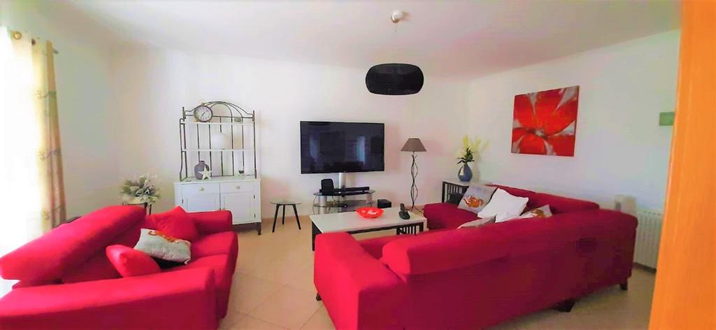 a living room with two red couches and a tv at Apartment in the center of Tavira with swimming pool and garage in Tavira