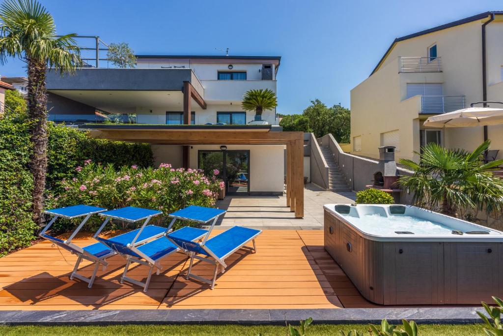 a deck with chairs and a hot tub in a yard at Relax Derossi 2 in Crikvenica