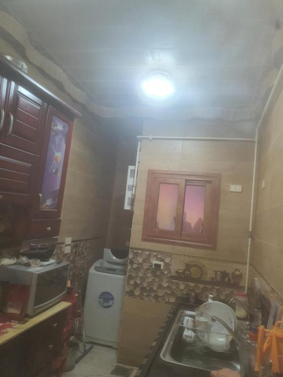 una pequeña cocina con fregadero y microondas en شقه الخامس en El Mansurá