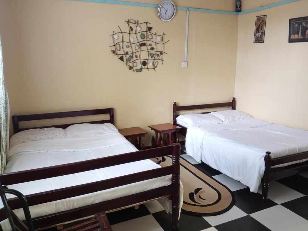 Kikuyu的住宿－Quiet Place，一间卧室设有两张床,墙上挂着一个时钟。