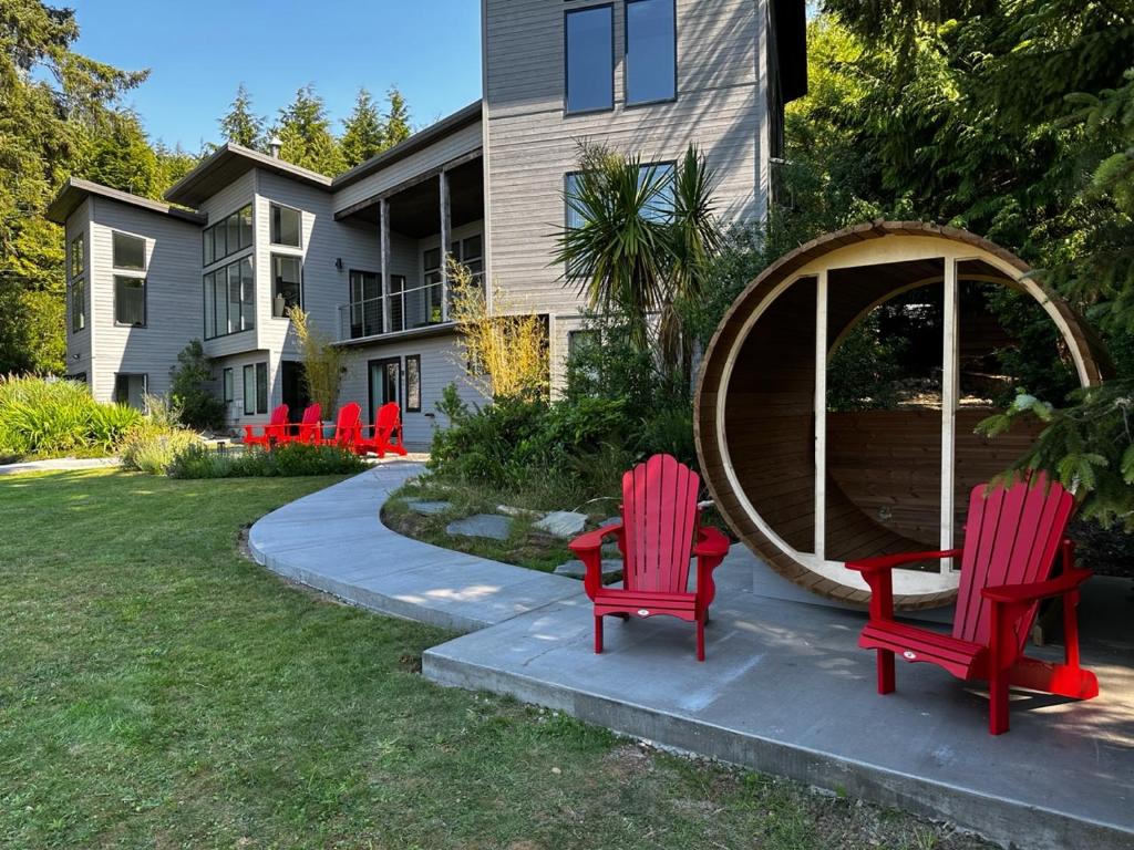 two red chairs and a gazebo in front of a house at Liahona Guest House in Ucluelet