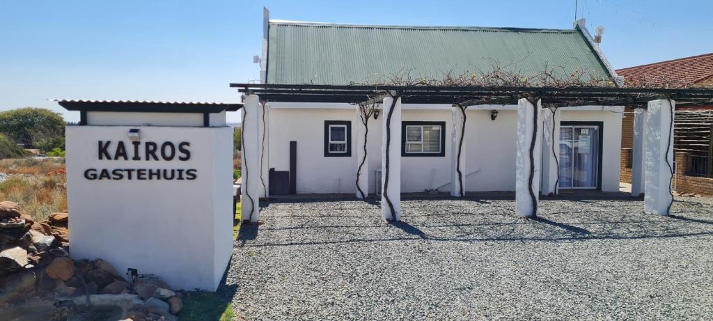 a white building with a sign in front of it at Kairos Guesthouse Orania in Orania