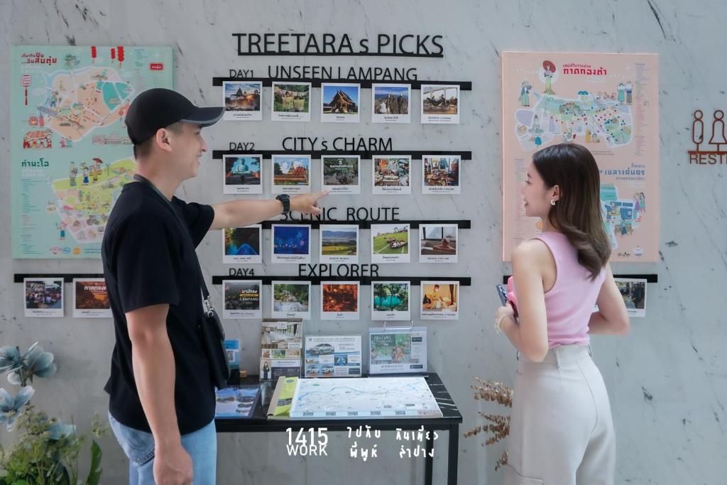 a man and a woman looking at a poster on a wall at Tree Tara hotel in Lampang