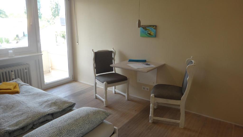 博登斯边的拉多夫采尔Auszeit am Bodensee的客房设有书桌、两把椅子和窗户。