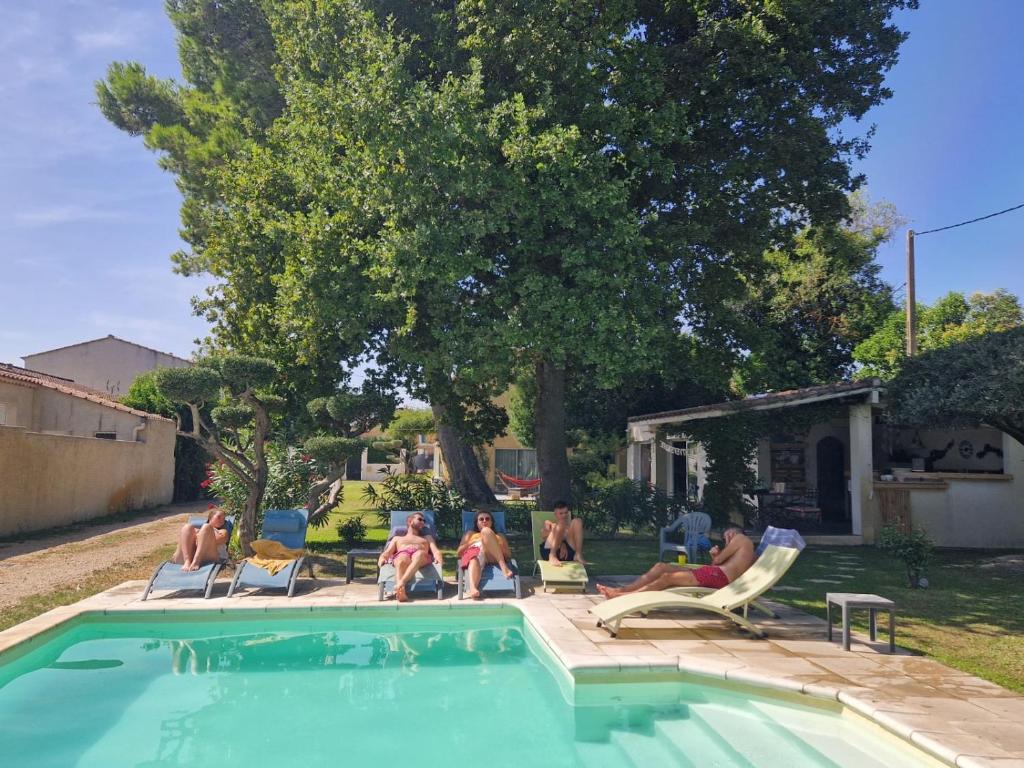 grupa mężczyzn siedzących na trawniku obok basenu w obiekcie Vacances révées au Pin Parasol w mieście Le Thor
