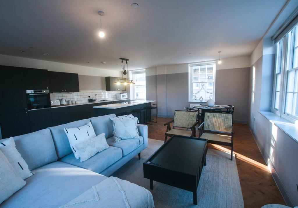 a living room with a blue couch and a kitchen at Bath Street Penthouse in Bath
