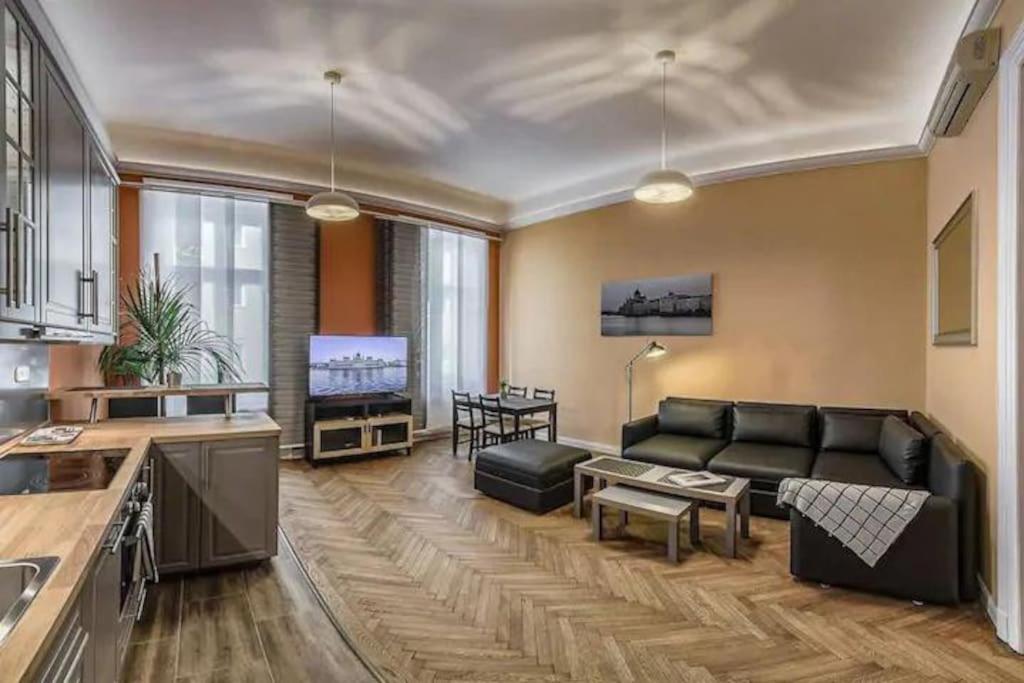 a living room with a black couch and a kitchen at Your Worry Free Apartment Close To Parliament in Budapest