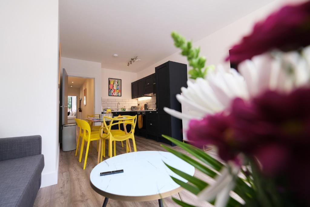 soggiorno e cucina con tavolo e sedie gialle di Brand New Ground Floor Apartment with Balcony a Londra
