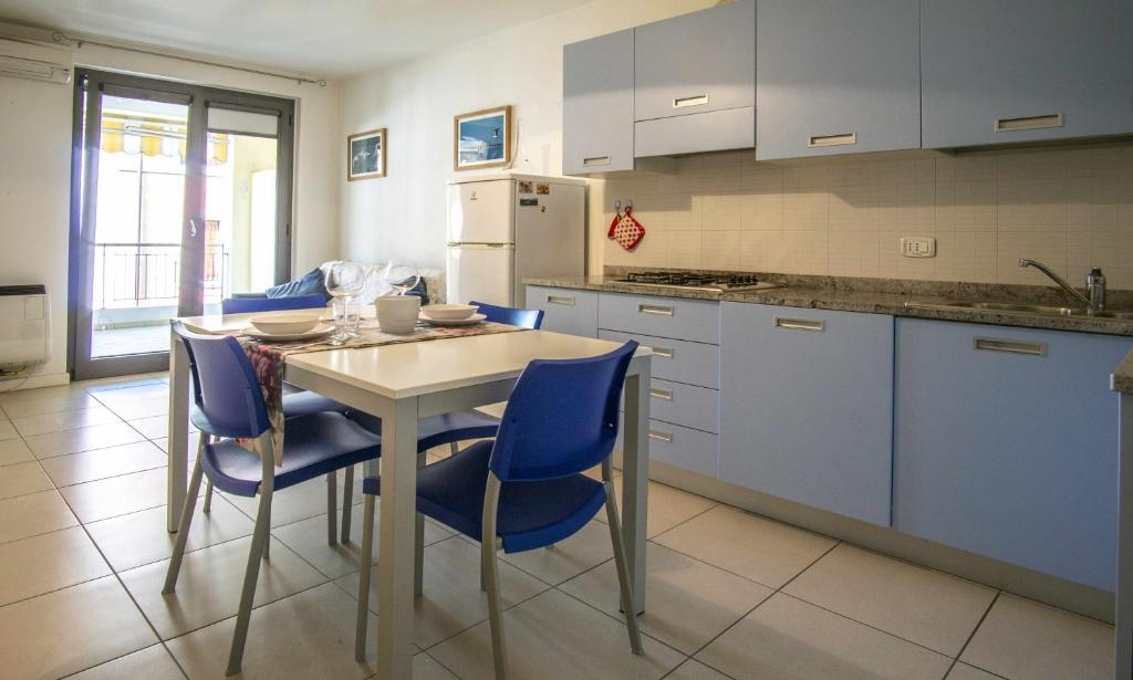 eine Küche mit einem Tisch und blauen Stühlen in der Unterkunft Gaia Apartment un gioiello in Grado