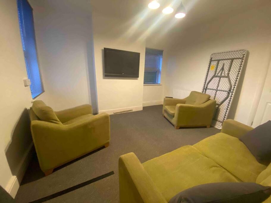 uma sala de estar com dois sofás amarelos e uma televisão em Silver Stag Properties, 4 BR Perfect for Groups em Hugglescote