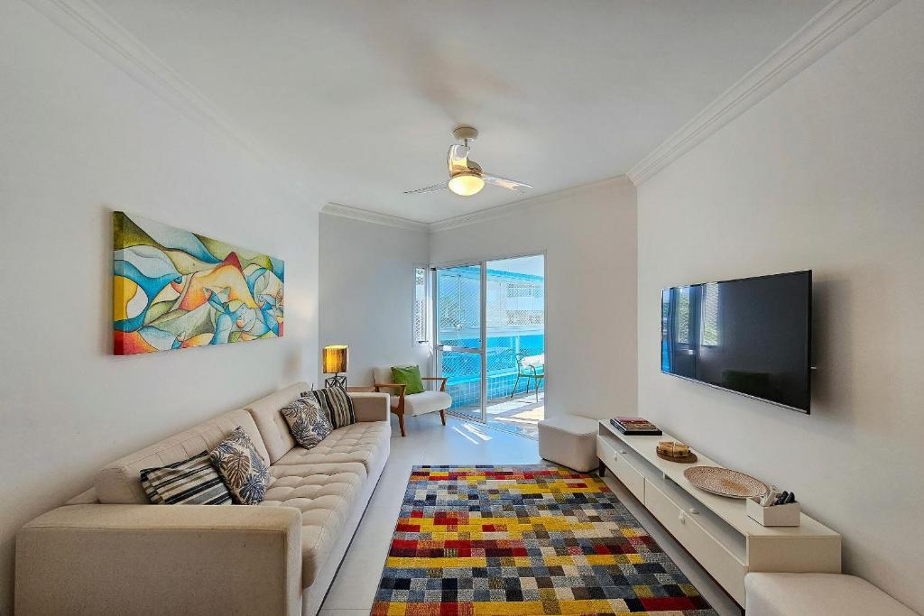 a living room with a couch and a flat screen tv at Condomínio com aptos e lazer completo na Riviera in Riviera de São Lourenço