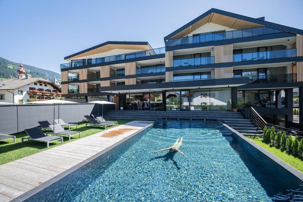 a dolphin swimming in a pool in front of a building at Montanaris Alpine - Active - Relax in Villabassa