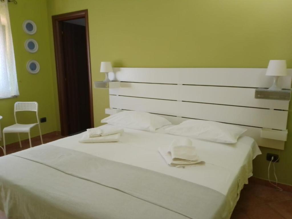 sypialnia z białym łóżkiem z dwoma kapeluszami w obiekcie Il sottosopra w mieście Labico